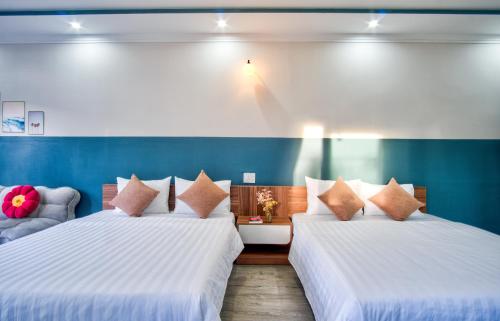 two beds in a room with blue walls at House of Pi Pleiku in Pleiku