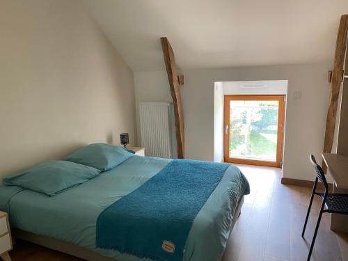 une chambre avec un lit avec des draps bleus et une fenêtre dans l'établissement Gîte La Longère, à Laillé