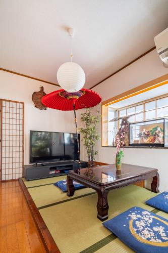 a living room with a table and a red umbrella at 新宿 新大久保駅108 平米日本庭園の宿 in Tokyo