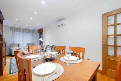 a dining room with a table with plates and wine glasses at Encantador piso con parking by CABANA Rentals in Vigo