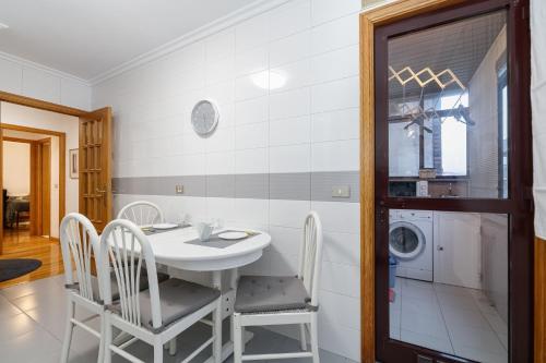 a kitchen with a table and chairs and a washing machine at Encantador piso con parking by CABANA Rentals in Vigo