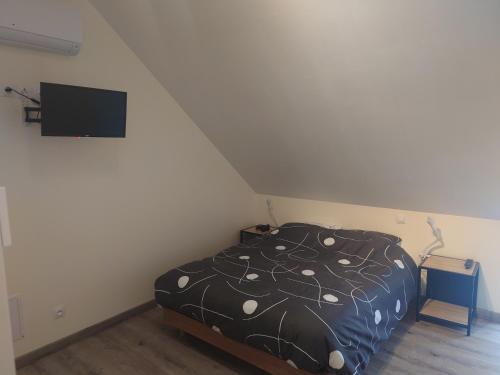 een slaapkamer met een bed en een flatscreen-tv bij Faites comme chez nous ! in Chilleurs-aux-Bois