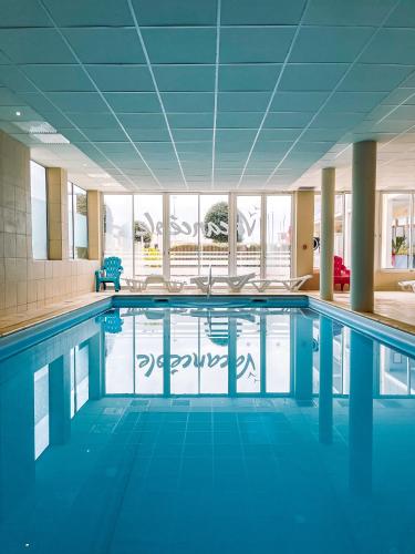 une piscine avec de l'eau bleue dans un immeuble dans l'établissement Appartement Cosy, terrasse vu mer, piscine, Sauna - WarmHouse, à Plougonvelin