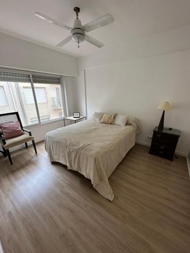 a white bedroom with a bed and a ceiling fan at Alberti Apartament in San Isidro
