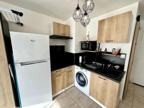 La cuisine est équipée d'un réfrigérateur blanc et d'un lave-vaisselle. dans l'établissement Appartement - Cap d'Agde, au Cap d'Agde