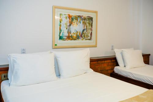two beds in a room with a picture on the wall at Mirai Beach Hotel in Natal