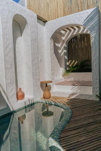 a room with a pool with a table and a chair at Anacardier Privé Hotel in Atins