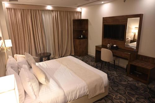 a hotel room with a bed and a desk and a television at فندق فيوليت الفندقية Violet Hotel in Yanbu