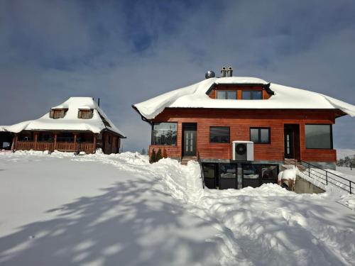 a house covered in snow next to another building at Zlatiborski biser in Suljagići