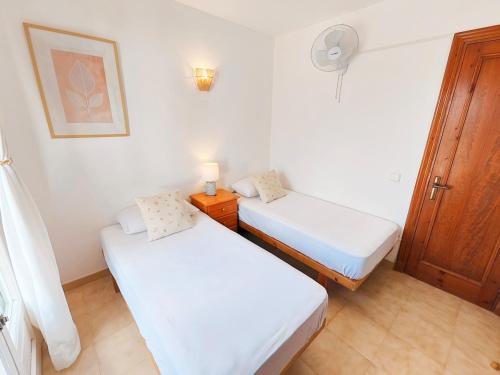 two beds in a small room with white walls at Villa Nuralux - Vistas Espectaculares, Piscina Privada y BBQ in Sant Climent