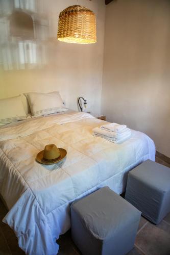 a hat on top of a bed with two stools at Casa en el corazón de Huacalera, Jujuy in Tilcara