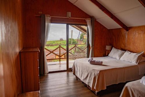 a bedroom with a bed and a large window at Cabañas Anavai Rapa Nui in Hanga Roa