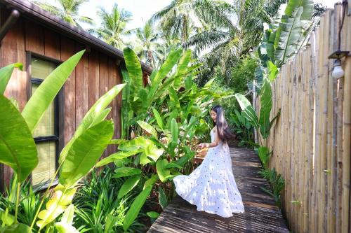 a woman in a dress walking down a wooden walkway at บ้านไร่มีสุข Baanrai Meesuk in Surat Thani