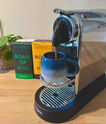 a coffee maker with a blue cup on a stand at The Shades - Bliss In The Heart of Windermere in Windermere