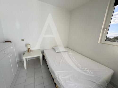 une petite chambre avec un lit et une table dans l'établissement Studio avec balcon et parking a 2 pas des plages, à Sète