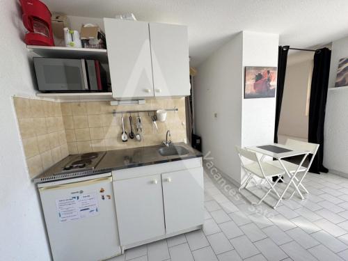 une cuisine avec des armoires blanches et une table et une chaise dans l'établissement Studio avec balcon et parking a 2 pas des plages, à Sète