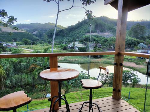 a balcony with two stools and a view of a lake at Domus Fiorese Chalés in Venda Nova do Imigrante