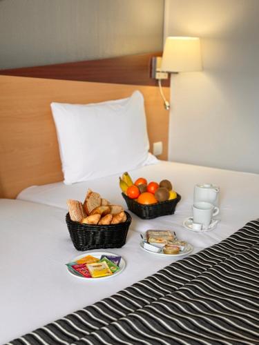 two baskets of fruit and bread on a bed at Kyriad Hotel Dijon Gare in Dijon