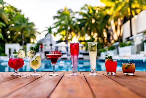 a group of wine glasses on a wooden table near a pool at Oh! Cancun - The Urban Oasis & Beach Club in Cancún