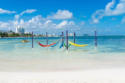 un grupo de hamacas en el agua en una playa en The Sens Cancun by Oasis - All Inclusive, en Cancún