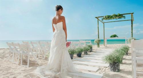 a woman in a wedding dress standing on the beach at The Pyramid Cancun by Oasis - All Inclusive in Cancún