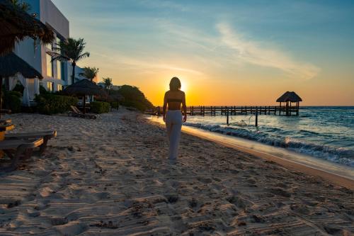 a woman walking on the beach at sunset at The Sens Tulum Riviera by Oasis in Akumal