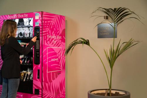 a woman standing in front of a pink refrigerator at Zedwell Hotel Piccadilly Circus in London