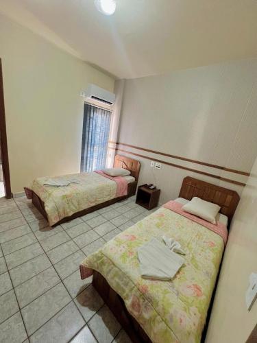 a hotel room with two beds and a window at Tulipa Hotel in Foz do Iguaçu