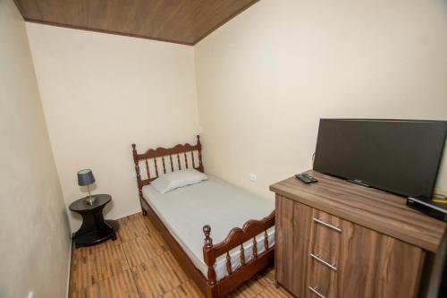 a small bedroom with a bed and a flat screen tv at Quinta Issazu in Juntas