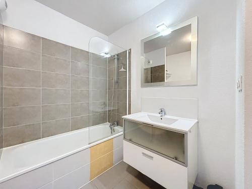 une salle de bain avec un lavabo, une baignoire et un miroir dans l'établissement 3356-Appartement 8 couchages, à Argelès-sur-Mer