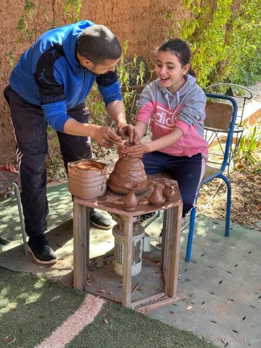 a man and a girl making a pot on a table at FEKHARA Country Club in Marrakech