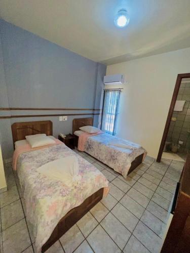 a bedroom with two beds and a window at Tulipa Hotel in Foz do Iguaçu