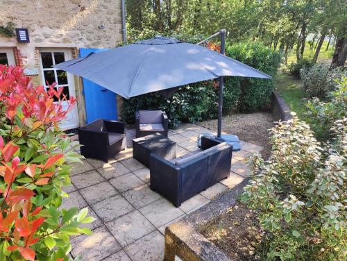 a patio with two chairs and an umbrella at Le Mas des Laurels in Chantemerle-lès-Grignan