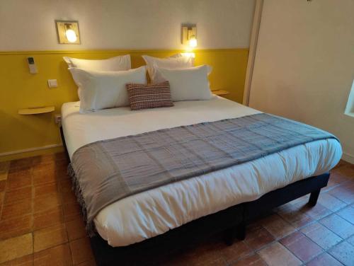 a large bed with white pillows in a room at Le Mas des Laurels in Chantemerle-lès-Grignan