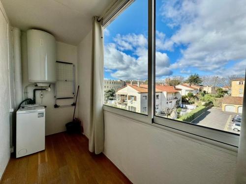 Cette chambre vide dispose d'une grande fenêtre et d'un réfrigérateur. dans l'établissement Le Cocon Méditerranéen, à Béziers