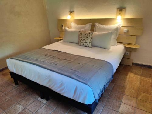 a bedroom with a large bed with white pillows at Le Mas des Laurels in Chantemerle-lès-Grignan