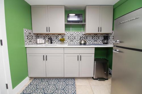 a kitchen with white cabinets and green walls at Exceptional & Central, Garden Suite, Top Amenities & Care! in Central Islip