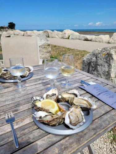une assiette d'huîtres sur une table avec des verres de vin dans l'établissement Charme et confort à St Martin de Ré avec terrasse & parking, à Saint-Martin-de-Ré