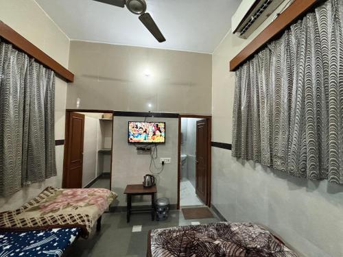a room with two beds and a flat screen tv at Shri Gaya Prasad Dham in Vrindāvan