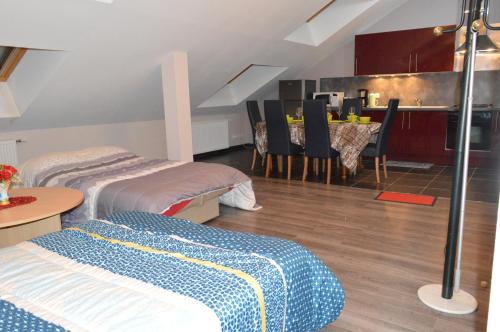 a room with two beds and a table and a kitchen at Rochire Location 1 in Gérardmer