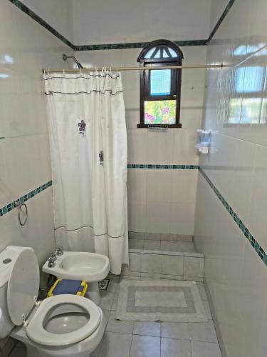 a bathroom with a toilet and a shower curtain at Departamento Santa Rita in Esquina