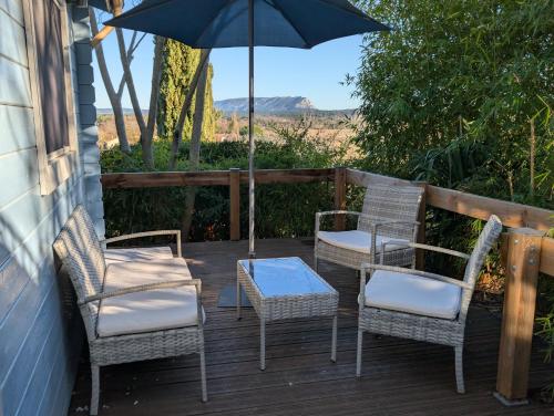 a patio with three chairs and an umbrella at Le Chalet Bleu - jacuzzi in Aix-en-Provence