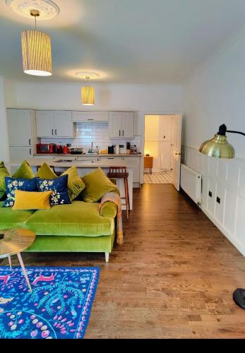 a living room with a green couch and a kitchen at Slateford House 1770 Luxury Aparthotel by The House of Danu in Edinburgh