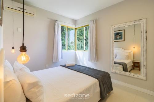 een slaapkamer met een bed en een spiegel bij Apto Vista Mar 240m da Praia em Jurerê IDO207 in Florianópolis
