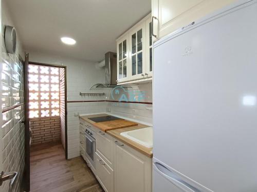 a kitchen with white cabinets and a sink and a refrigerator at Ayf mar azul primera línea de playa morro in Oropesa del Mar