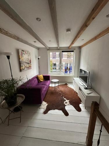 a living room with a purple couch and a tv at 't Kleinste huisje van Arnhem in Arnhem