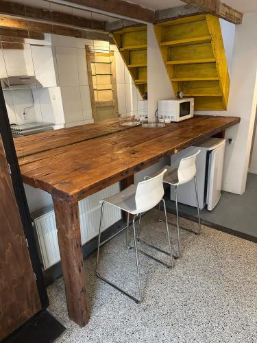 a large wooden counter in a kitchen with white chairs at 't Kleinste huisje van Arnhem in Arnhem