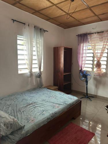 ein Schlafzimmer mit einem Bett und zwei Fenstern in der Unterkunft Maison de vacances Calavi séminaire in Abomey-Calavi
