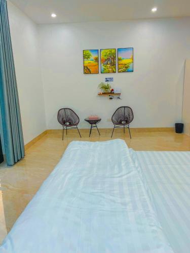 a bedroom with a large bed and two chairs at Tamcoc Motel in Văn Lâm