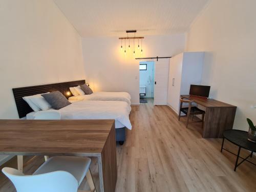 una camera da letto con due letti, un tavolo e una scrivania di Zonnekus Guesthouse a Città del Capo